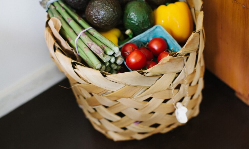 bunch of assorted heirloom vegetables and produce in brown wicker basket